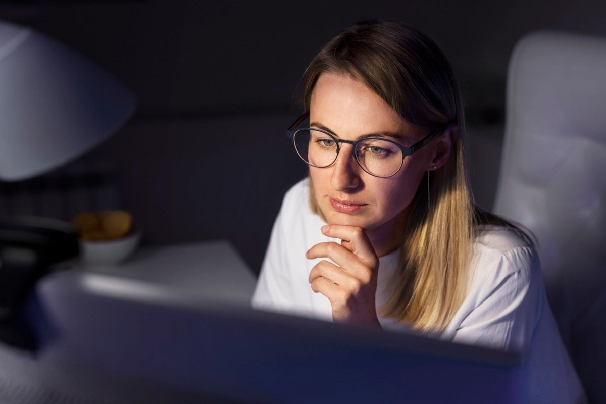 Mujer con gafas frente al computador de noche